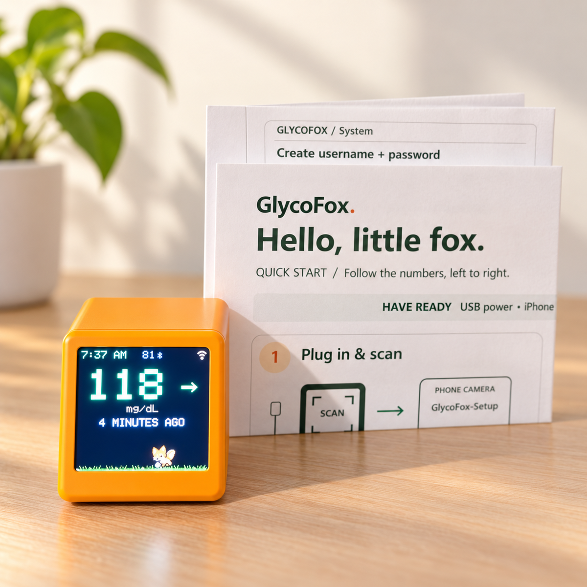 Orange GlycoFox desktop glucose display beside the included quick-start guide
